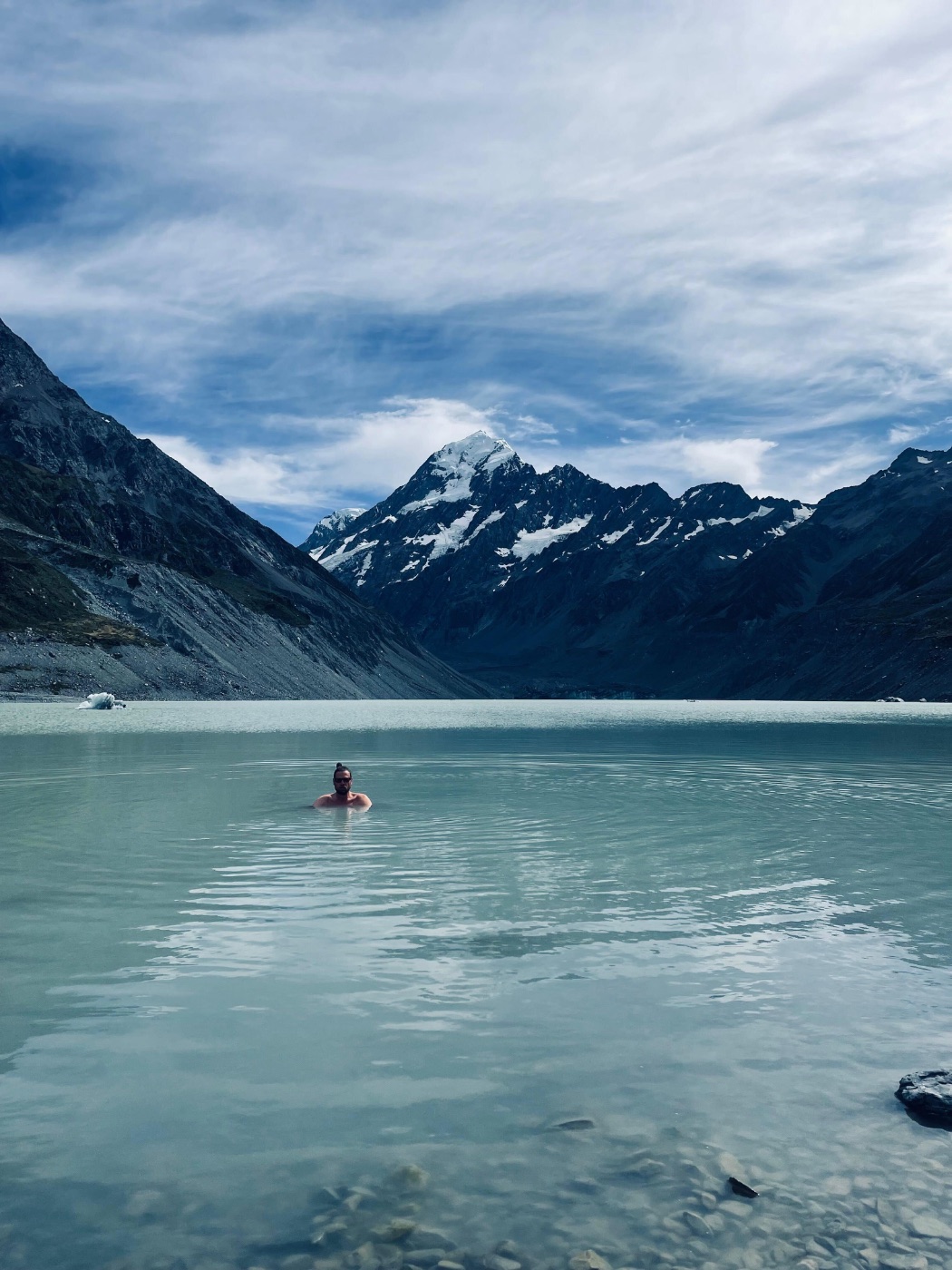 Tom Rosenstein bathing in a glacier lake with a mountain backdrop